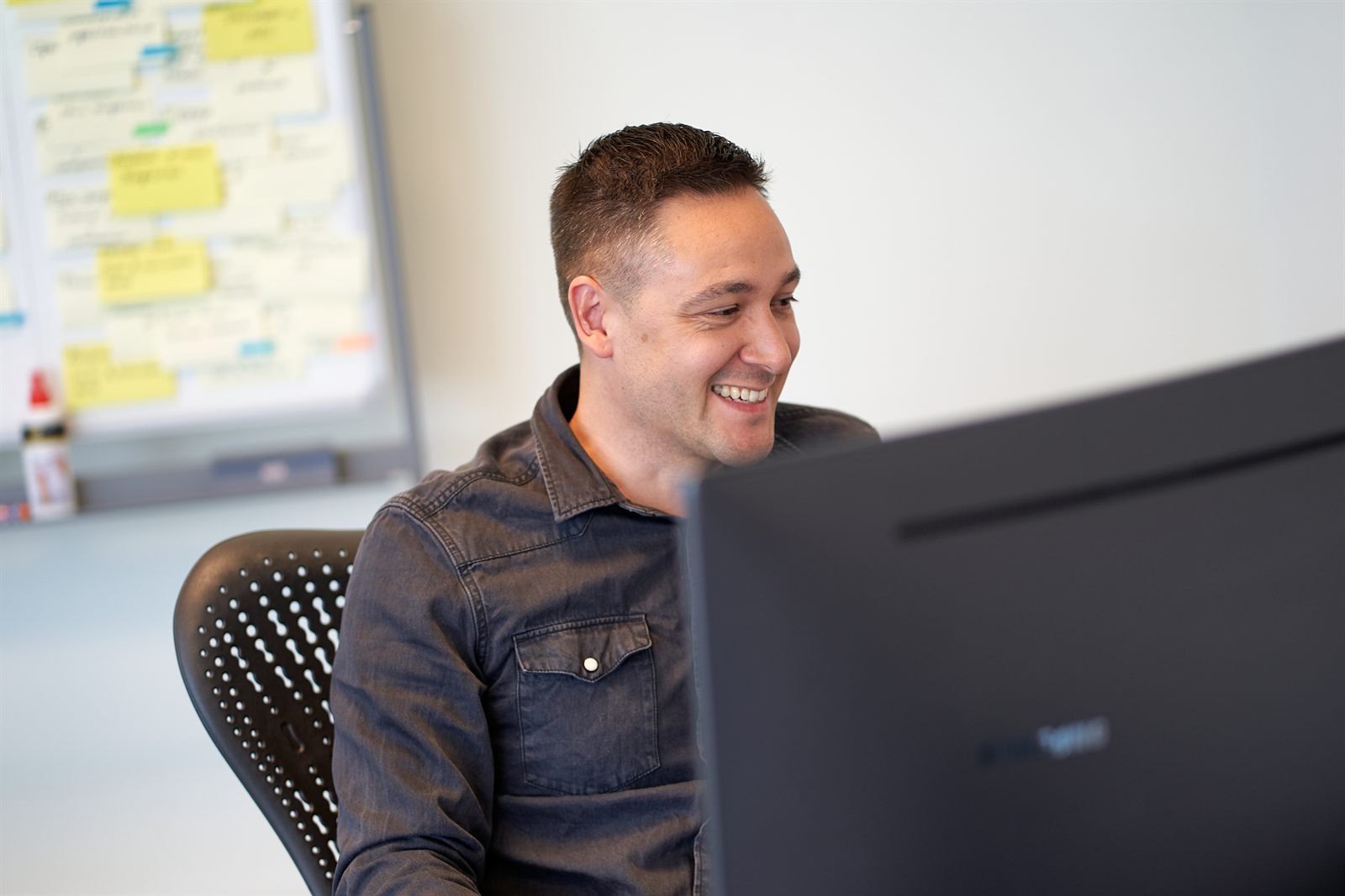 An Orange Warriors colleague laughing while working at their screen